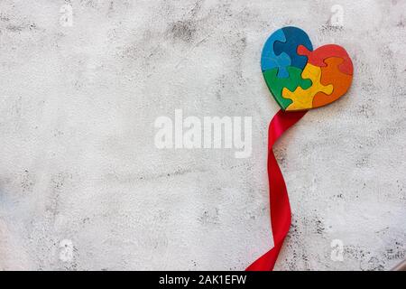 Wooden multicolor puzzle in the form of heart on gray background. Concept valentines day, relationship. Stock Photo