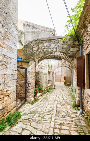 Typical narrow cobbled alleyway with stone arches in the historic old town in Bale, a small hill town on Mont Perin in Istria County, Croatia Stock Photo