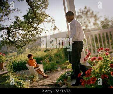 Mid-adult man bringing his wife a snack in their back yard. Stock Photo