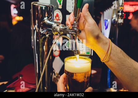 Mans hand pouring pint of beer behind the bar Stock Photo