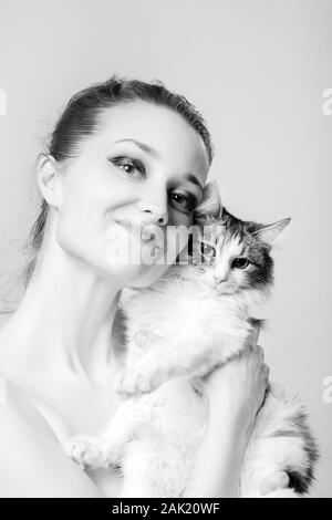 happy young woman with her fluffy cat on white background looking at camera, smiling, monochrome Stock Photo