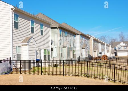 Row of generic houses from backyard view showing yards and fences in a southeast U.S. suburb on a beautiful sunny blue sky day. Stock Photo