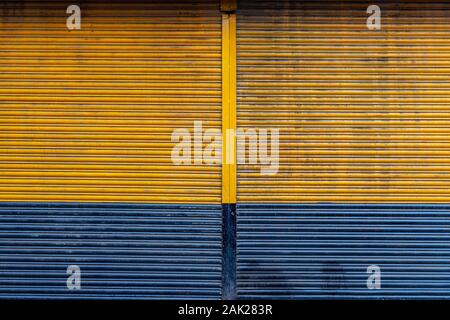 Yellow and blue color rolling steel shutter door background. Stock Photo