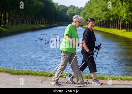 Two German senior women enjoy nordic walking in Kassel city park Germany old people European seniors training Stock Photo
