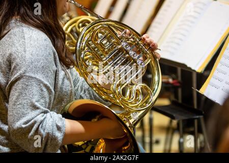 Young woman playing on french horn during philharmonic concert Stock Photo