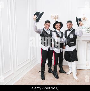 three male dancers in national costumes standing in the cabaret hall. Stock Photo