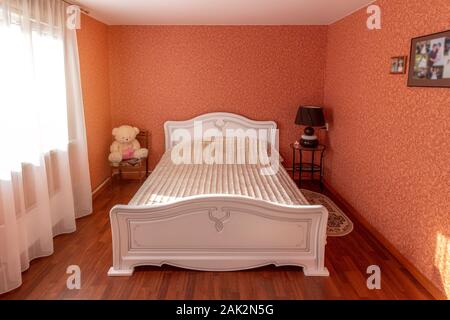 White antique furniture in a bedroom with red walls. Stock Photo
