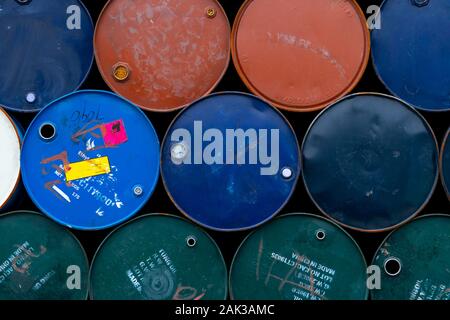Old chemical barrels. Blue, green, orange oil drum. Steel oil tank. Toxic waste warehouse. Hazard chemical barrel with warning label. Industrial waste Stock Photo