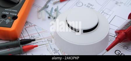 smoke detector with a screwdriver and a measuring device on a circuit diagram Stock Photo