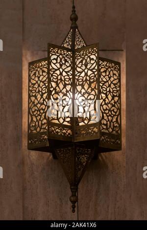 Lit, Moroccan, Arabian lamp with intricate decor hanging on wall. Concept for Moroccan and Arabian culture and design. Stock Photo