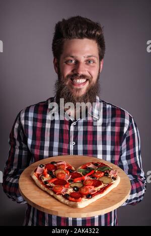 Happy smiling man holding home made heart shaped pizza for Valentines day Stock Photo