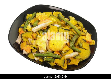 baked vegetable chips which include sweet potatoes, green beans, taro, and squash in a black colored bowl. Isolated on white. Stock Photo