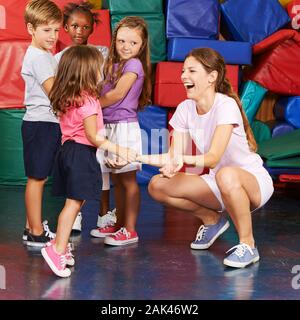 Girl jumps at the childrens gymnastics in kindergarten at the hand of the educator Stock Photo