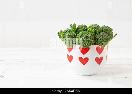 Fresh green broccoli sprouts in a dish covered in hearts. Stock Photo