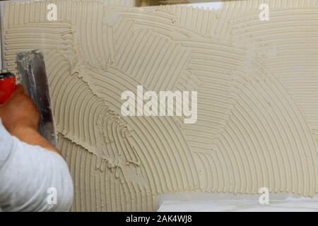 Spreading wet mortar before applying tiles on bathroom floor tile. Stock Photo