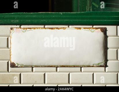 Blank metallic plate on an antique wall tiled with Metro tiles background. Stock Photo