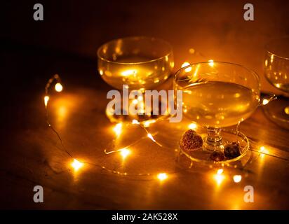 Two cocktail glasses with berries and lights glowing on wooden background still life Stock Photo