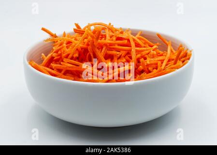 Carrots sliced in a white bowl, isolated on white background Stock Photo