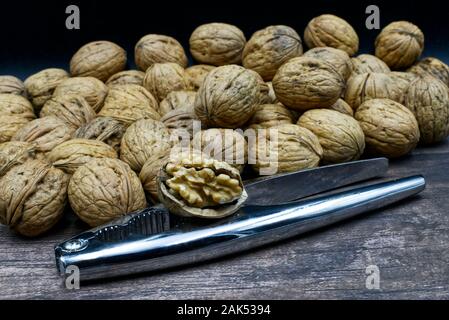 Walnuts with metal nutcracker on a wooden background Stock Photo