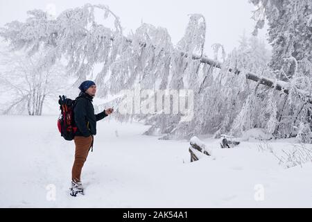 Young man taking photos of a snow covered winter landscape Stock Photo
