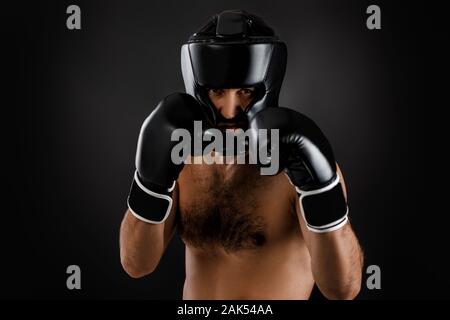 Muscular boxer man with boxing gloves ready to fight on black background. man wearing protective gear Stock Photo