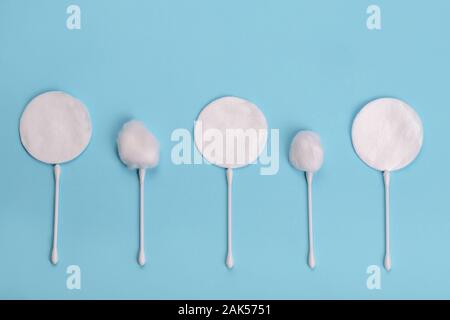 Cotton pads and sticks on the blue background in shape of flowers Stock Photo