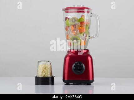 Red blender with fruits inside and the garlic chopper isolated on white background Stock Photo