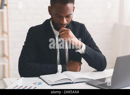 Close up portrait of pensive afro man economist working with papers in office Stock Photo