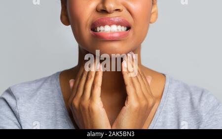 Close up of afro woman rubbing her inflamed tonsils, tonsilitis problem, cropped Stock Photo