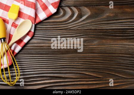 Red checkered napkin and kitchen utencils on brown wooden kitchen table with copy-space. Top view Stock Photo