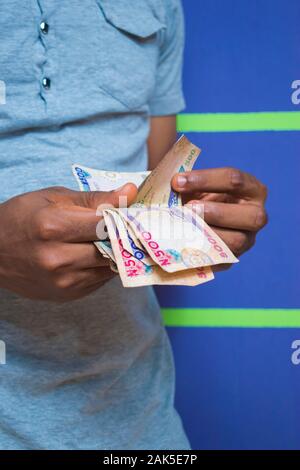 a young African Nigerian man counting his money Stock Photo