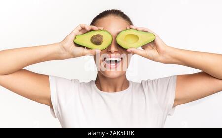 Healthy Fats. Woman Covering Eyes With Avocado Halves Having Fun Posing In Studio On White Background. Stock Photo