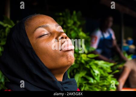 beautiful young african woman with scarf and eyes closed and natural face with head tilted up relaxing herself and clearing her mind Stock Photo