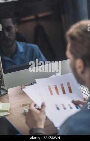 Working on schemes. Young bearded man in blue shirt working with schemes Stock Photo