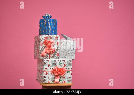 stack of gift boxes on a chair in front of a pink background Stock Photo