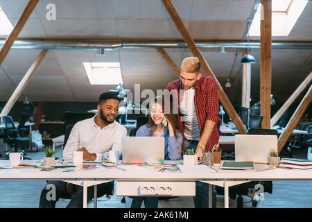 Programmers working together on laptop late at night, coding new program on computer Stock Photo