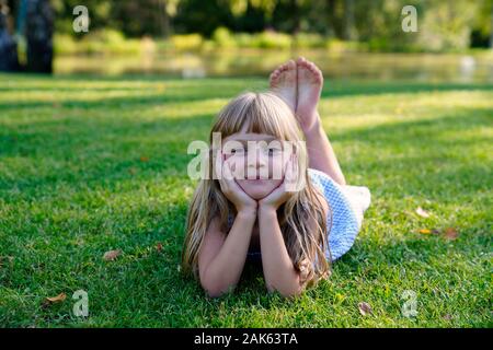 Girl lying on a meadow with her head propped up, 6 years, portrait, Czech Republic Stock Photo