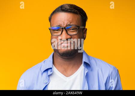 Disgust. Afro Guy Grimacing Feeling Aversion Looking At Camera Standing Over Orange Background. Studio Shot Stock Photo