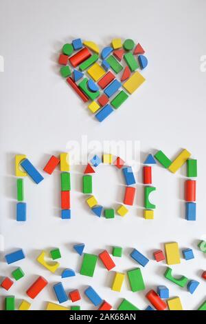 colorful wooden toy blocks lettering the word MOM and a heart on white background Stock Photo