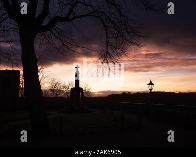 War Memorial in the Castle Grounds silhouetted against a sunset sky at Knaresborough North Yorkshire England