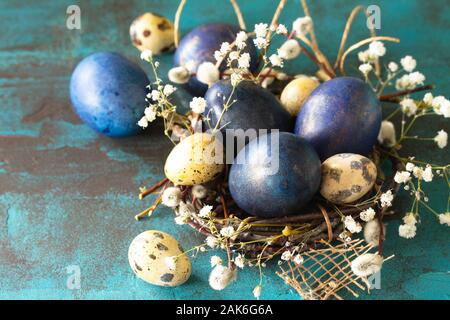 Blue easter eggs in a nest on a blue stone or slate background. Stock Photo