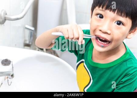 Little asian boy with toothbrush cleaning teeth in the bathroom. Close up kid brushing his teeth. health care and dental hygiene concept. Stock Photo