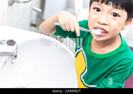 Little asian boy with toothbrush cleaning teeth in the bathroom. Close up kid brushing his teeth. health care and dental hygiene concept. Stock Photo