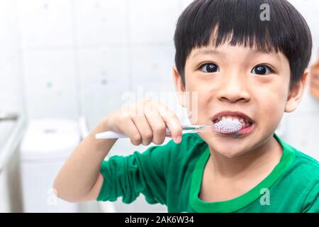 Little asian boy with toothbrush cleaning teeth in the bathroom. Close up kid brushing his teeth. health care and dental hygiene concept. Stock Photo