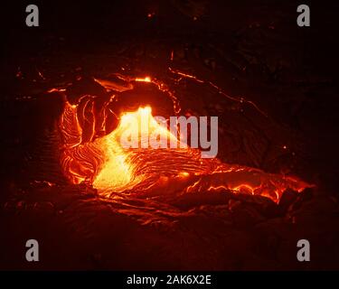 Detailed view of an active lava flow, hot magma emerges from a crack in the earth, the glowing lava appears in strong yellows and reds - Location: Haw Stock Photo
