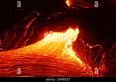 Detailed view of an active lava flow, hot magma emerges from a crack in the earth, the glowing lava appears in strong yellows and reds - Location: Haw Stock Photo