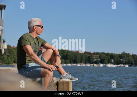One male person with sunglasses enjoying Finnish midsummer by sea in Finnish capital Helsinki Stock Photo