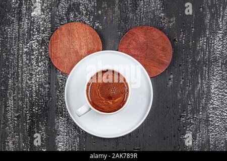 Traditional Turkish coffee in ceramic cup on black wood table. Served on the table with a glass of water and chocolates. Stock Photo