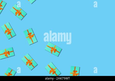 Holiday card. Mint gift boxes with orange ribbon on blue background. Flat lay, top view. Stock Photo