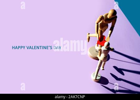 Two wooden men hold their hearts in their hands. On a pink background. Stock Photo